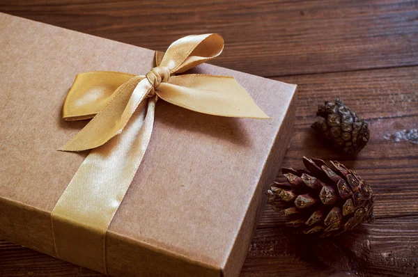 礼品盒与金弓和锥云杉木材背景 — 图库照片