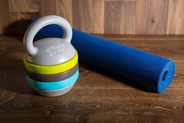 Ayarlanabilir kettlebell ve mat fitnes ahşap arka plan için. Bir fitness eğitimi için ağırlıklar.