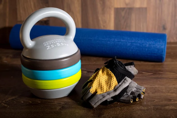 Ayarlanabilir kettlebell, halter ve yoga mat ahşap arka plan üzerinde döngü eldiven. Bir fitness eğitimi için ağırlıklar.