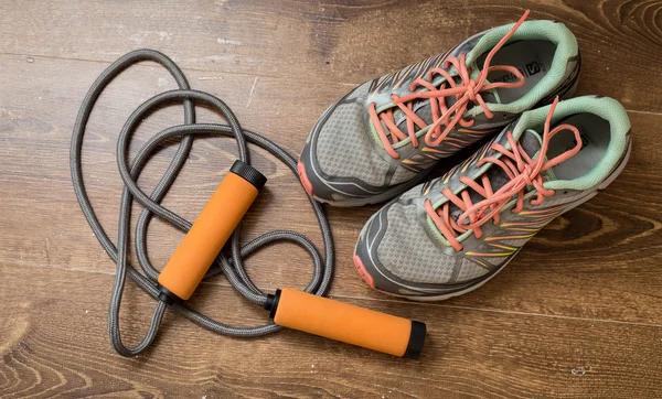 Spor ayakkabı, ahşap arka plan üzerinde turuncu dumbbells çifti.