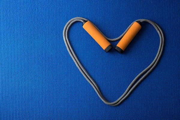 Kalp mavi yoga mat arka plan üzerinde ip atlama üzerinden