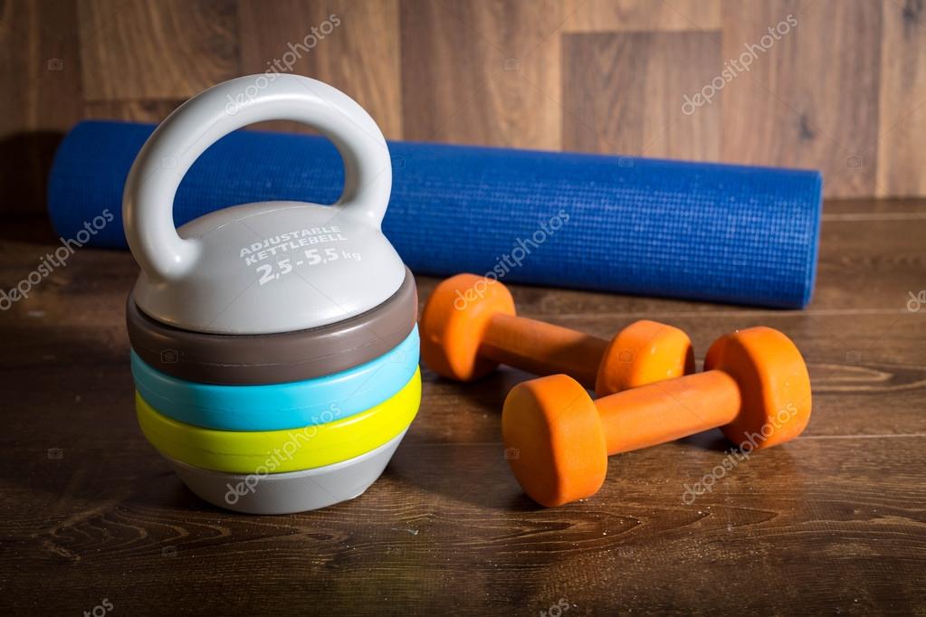 Adjustable Kettlebell Pair Of Orange Dumbbells And Yoga Mat On