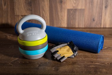 Ayarlanabilir kettlebell, döngüsü eldiven ve yoga mat ahşap arka plan üzerinde. Bir fitness eğitimi için ağırlıklar.
