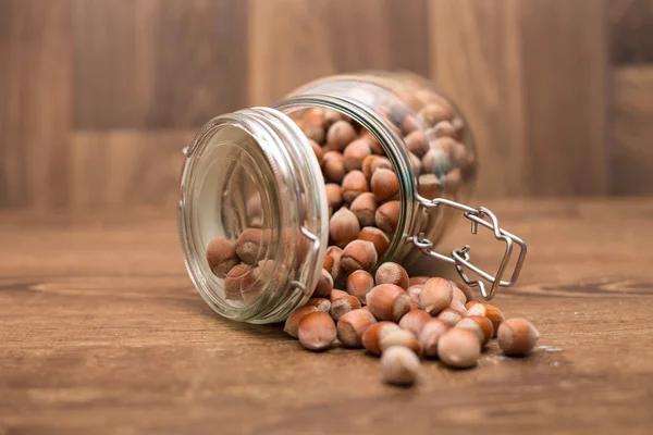 Fındık ahşap bir masa üzerinde Cam Kavanoz dışarı dökülme