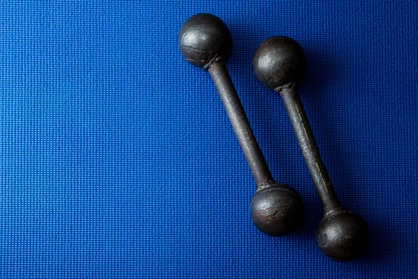 Retro Iron Grunge Hanteln auf blauem Yogamatte Hintergrund — Stockfoto