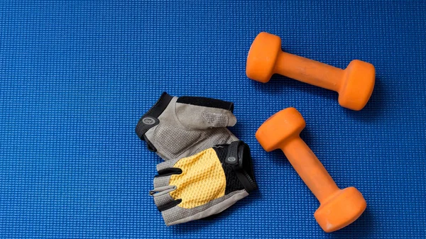 Turuncu dumbell ve döngüsü eldiven mavi yoga mat zemin üzerine çift.