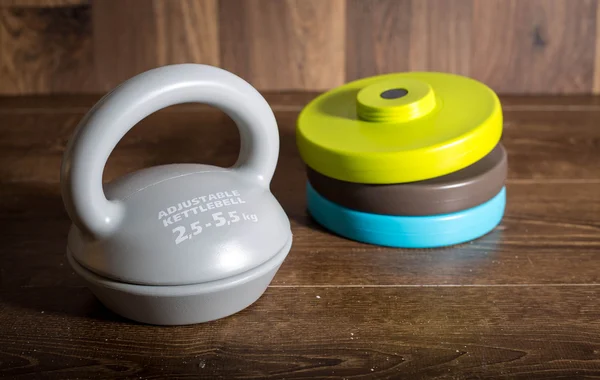 Kettlebell ajustable sobre fondo de madera. Pesas para un entrenamiento de fitness . Imagen de stock