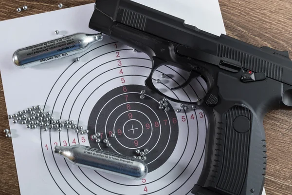 Siyah pnömatik tabanca (Hava tabancası), iki gaz tüpleri, bir hedef ve madde işaretleri