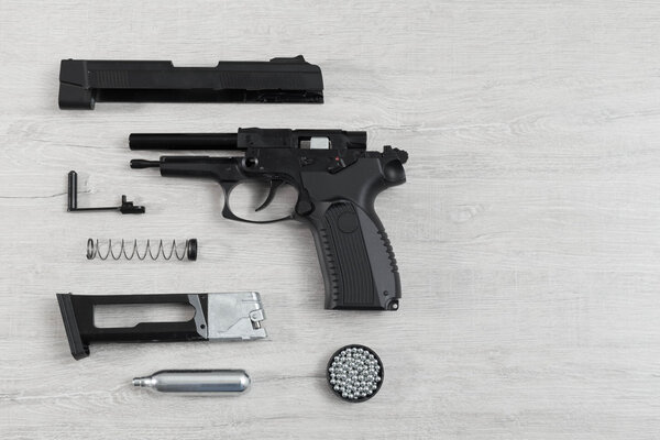 Black pneumatic pistol (air gun) gun unassembled on a lighten background