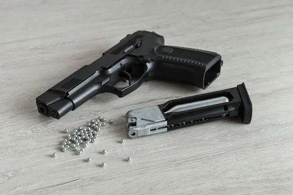 Pistola de aire y piezas de repuesto para armas se encuentran en el fondo de la luz Fotos de stock libres de derechos