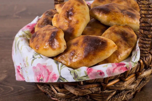 Orosz pirozhki (sült pogácsa), a kosárban, fa tábla — Stock Fotó