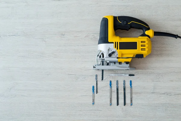 Electric fretsaw and drills on a light wooden table — Stock Photo, Image