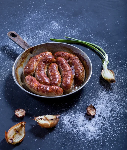 Lezzetli fırında sosis tava ve ızgara soğan koyu arka plan üzerinde. 