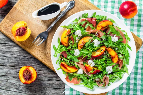 Salade de pêches, roquette, prosciutto et fromage de chèvre avec balsamique — Photo