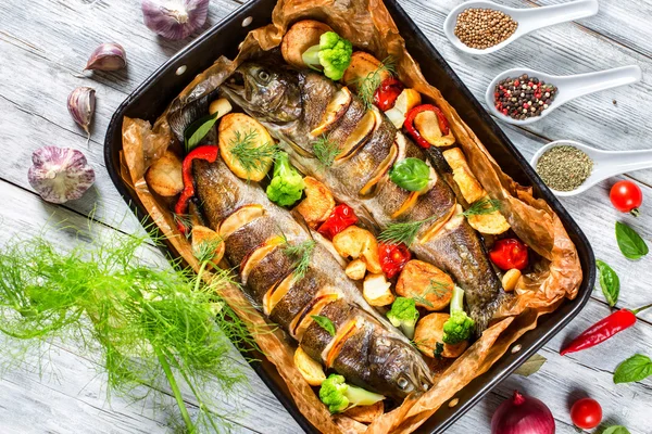 Forel vissen gebakken met tomaten, aardappelen, broccoli, citroen — Stockfoto