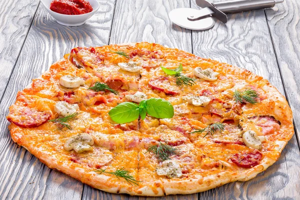 Pizza con salchichas, jamón, champiñones y queso, primer plano — Foto de Stock