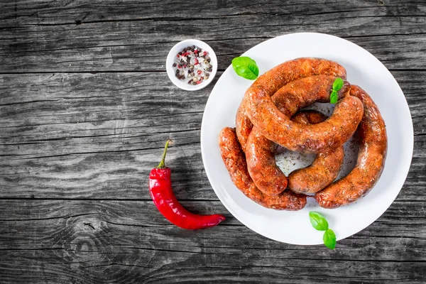 Gegrilde worstjes zijn op de witte schotel, bovenaanzicht — Stockfoto