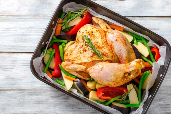 Pollo entero crudo con coloridos trozos de pimientos, patatas. primer plano —  Fotos de Stock