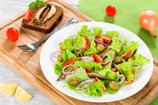 Kirschtomaten, rote Zwiebeln, grüne Oliven, Salatblätter, geräucherte Sprotten — Stockfoto