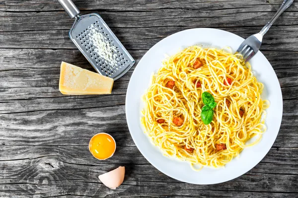 Spaghetti Carbonara, bazylia, żółtka jaj, tarto parmezan, boczku, zbliżenie — Zdjęcie stockowe