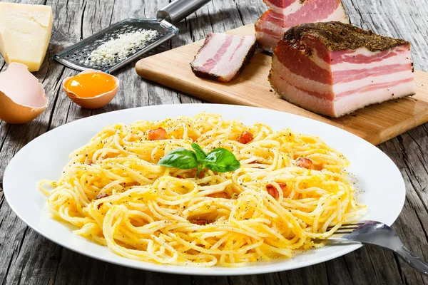 Spaghetti Carbonara, bazylia, żółtka jaj, tarto parmezan, boczku, zbliżenie — Zdjęcie stockowe