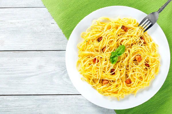 Espaguetis carbonara, albahaca, yema de huevo, queso parmesano rallado, tocino, primer plano — Foto de Stock