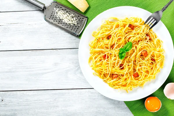 Spaghetti carbonara, basil, eggs yolk, grated parmesan cheese, bacon, close-up — Stock Photo, Image