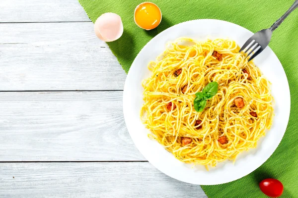 Spaghetti Carbonara, bazylia, żółtka jaj, tarto parmezan, boczku, zbliżenie — Zdjęcie stockowe