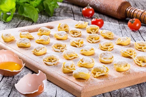 Ahşap kesme tahtası üzerinde İtalyan tortellini Bolognesi, yakın çekim, üst görünüm — Stok fotoğraf