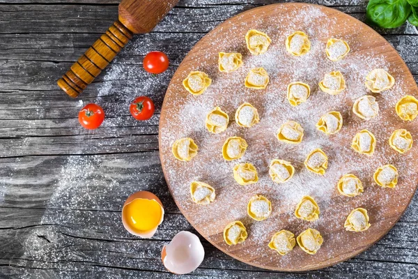 Włoski tortellini Bolognesi na drewnianej deski do krojenia, zbliżenie, widok z góry — Zdjęcie stockowe