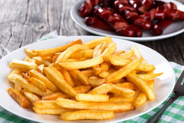 Smakelijke Franse frietjes op plaat, op houten tafel achtergrond — Stockfoto