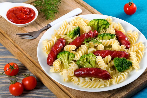 Pasta salad with broccoli and grilled sausages, top view — Stock Photo, Image