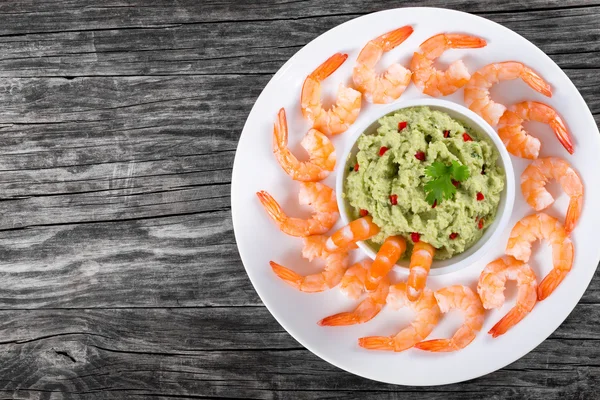 Langostinos en un plato blanco con salsa de guacamole en un tazón en un viejo — Foto de Stock