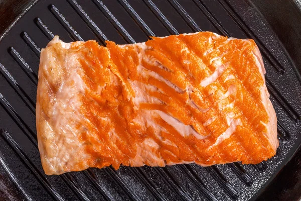 Salmon steak on a iron gril pan — Stock Photo, Image
