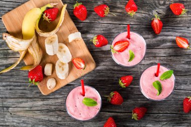Strawberry Banana milk shake Cups on an old wooden table clipart