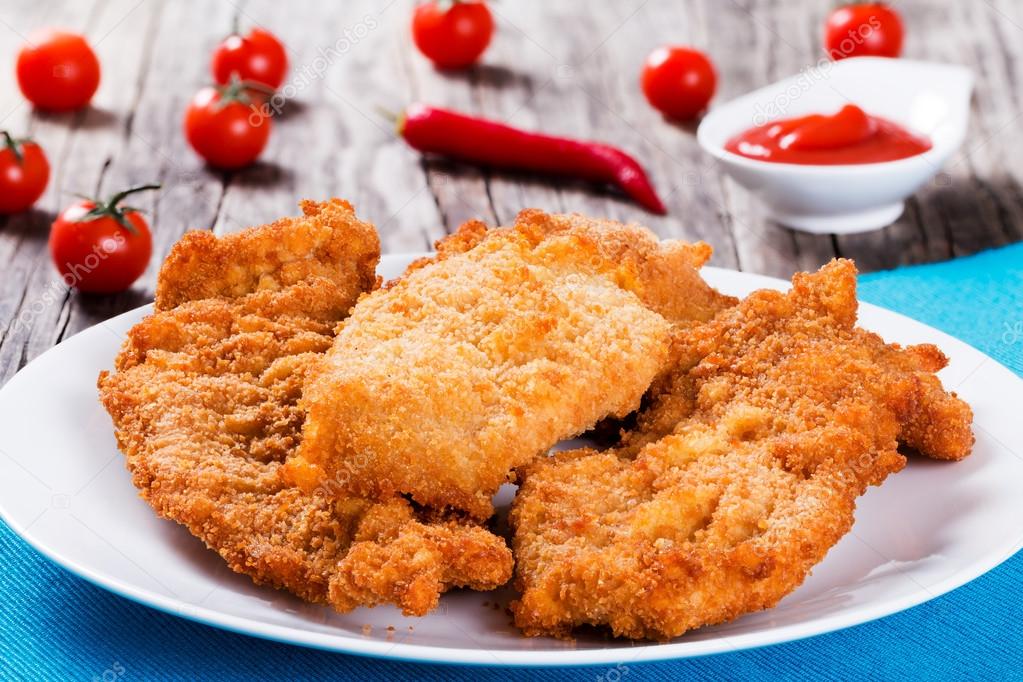 Bread Crumb Coated Fried Chicken breast on a white dish Stock Photo by