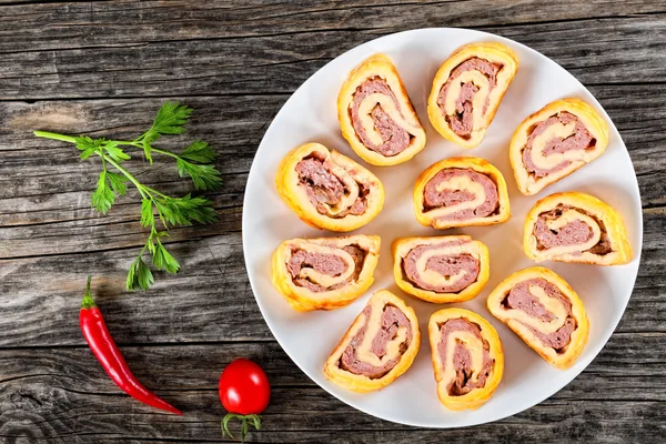 Tasty baked cheese meat Roll-Ups on white dish — Stock Photo, Image