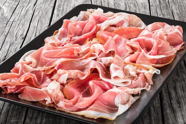 Kıvrılmış lezzetli İtalyan Prosciutto, dilim yakın çekim — Stok fotoğraf