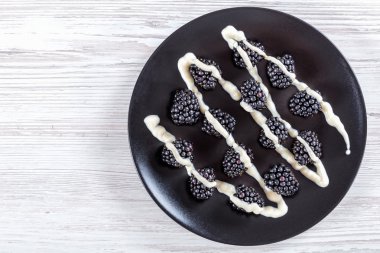 Fresh organic blackberries on black plate, top view clipart