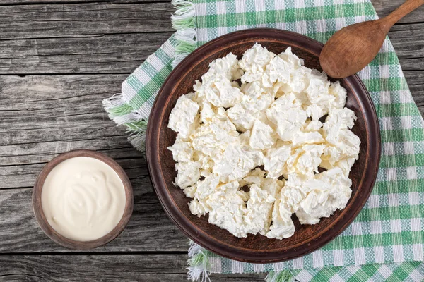 Queijo cottage em prato de barro com colher de madeira — Fotografia de Stock