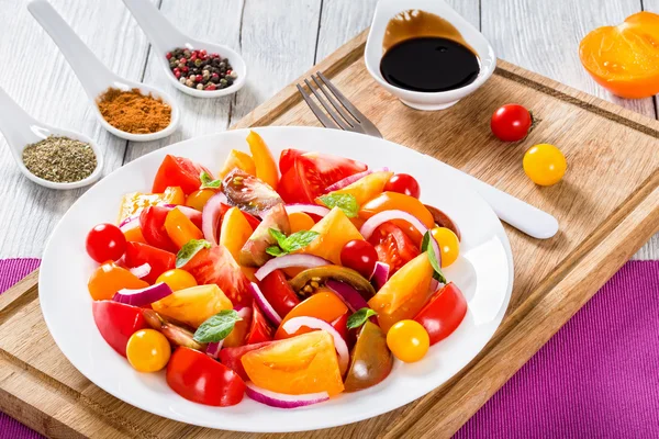 Tasty tomato salad with red onion, mint leaves on white dish — Stock Photo, Image