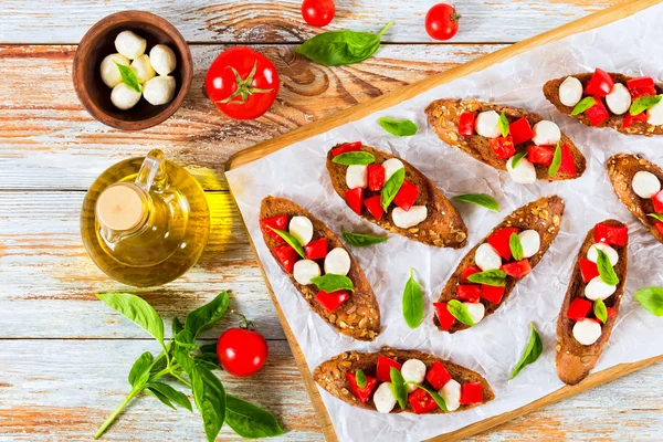 Bruschetta con tomates, mini mozzarella y hojas de albahaca — Foto de Stock