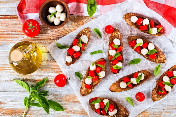 Bruschetta with tomatoes, mozzarella and basil on  rye baguett — Stock Photo, Image