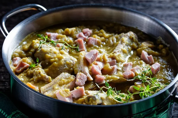 Green peas finnish soup with pork ribs and ham in a pot, horizontal view from above, macro — Stock Image Green Peas Finnish Soup Pork Ribs Ham Pot Horizontal View Royalty Free Stock Photos