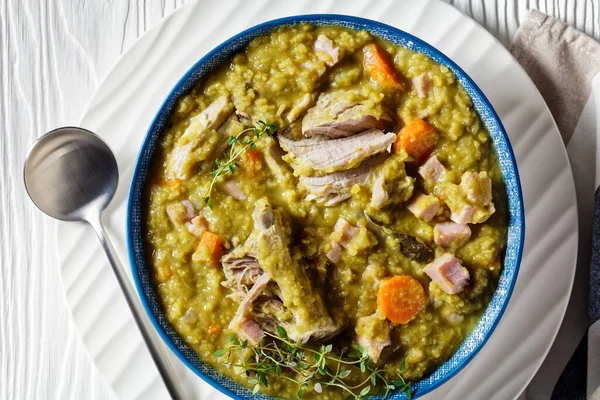 Green peas finnish soup with pork ribs and ham in a blue bowl, horizontal view from above, flat lay, close-up — Stock Image Green Peas Finnish Soup Pork Ribs Ham Blue Bowl Horizontal Stock Image