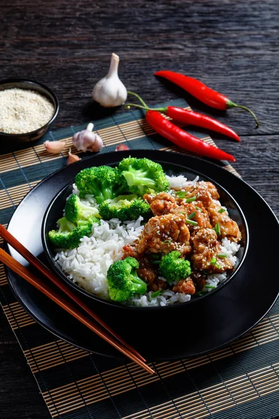 左将军的鸡排脆脆的中国鸡排在一个黑碗里 上面有米饭和蒸西兰花小花 从上往下看 — 图库照片