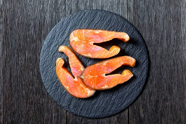 Slices of cold-smoked arctic char on a round slate on a dark wooden background, top view, close-up — Stock Image Slices Cold Smoked Arctic Char Slate Dark Wooden Background Top Stock Photo