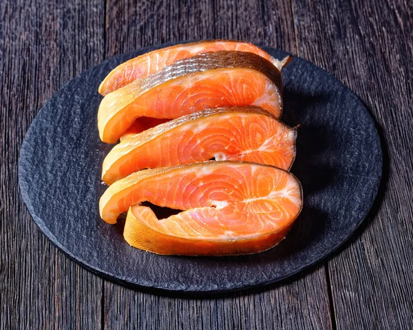 Slices of cold-smoked arctic char on a round slate on a dark wooden background, top view, close-up — Stock Image Slices Cold Smoked Arctic Char Slate Dark Wooden Background Top Stock Photo