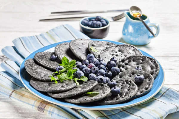 Panqueca Doce Preta Servida Com Mirtilos Hortelã Uma Placa Azul — Fotografia de Stock