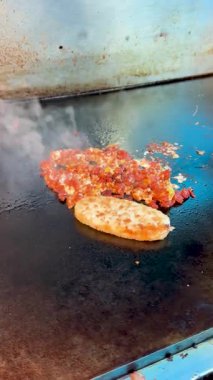 Doğranmış sucuk ve tek bir haşlanmış sığır eti. Düz bir ızgarada pişiyor. Isı altında kaynıyor..